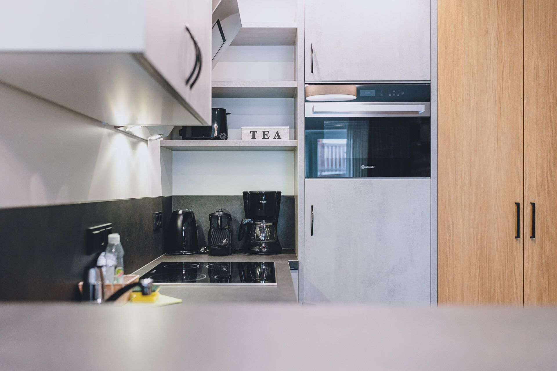 A modern kitchen with a built-in coffee maker, a tea station, and a microwave.