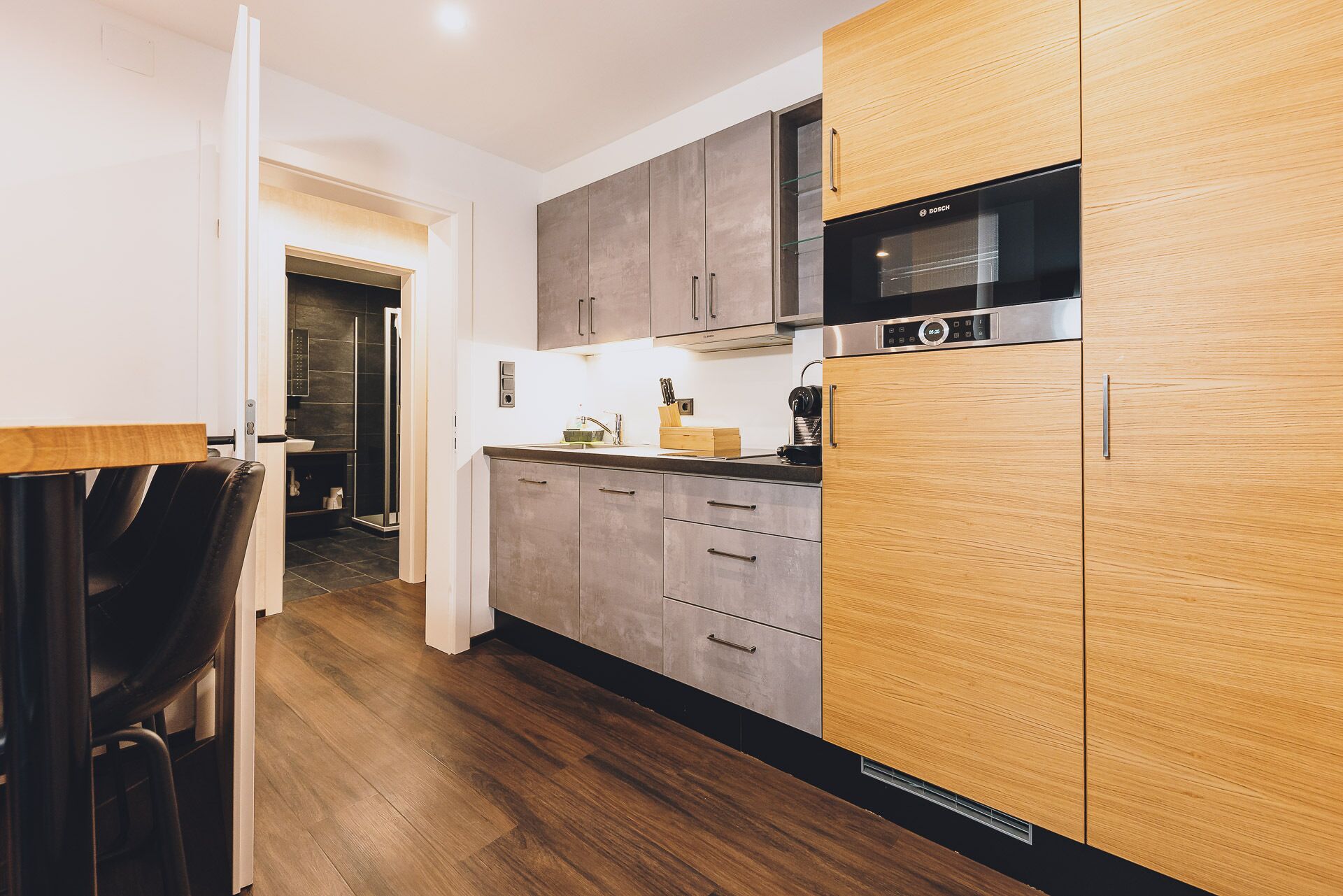A modern kitchen with grey cabinets, a Bosch microwave, and a wooden countertop.