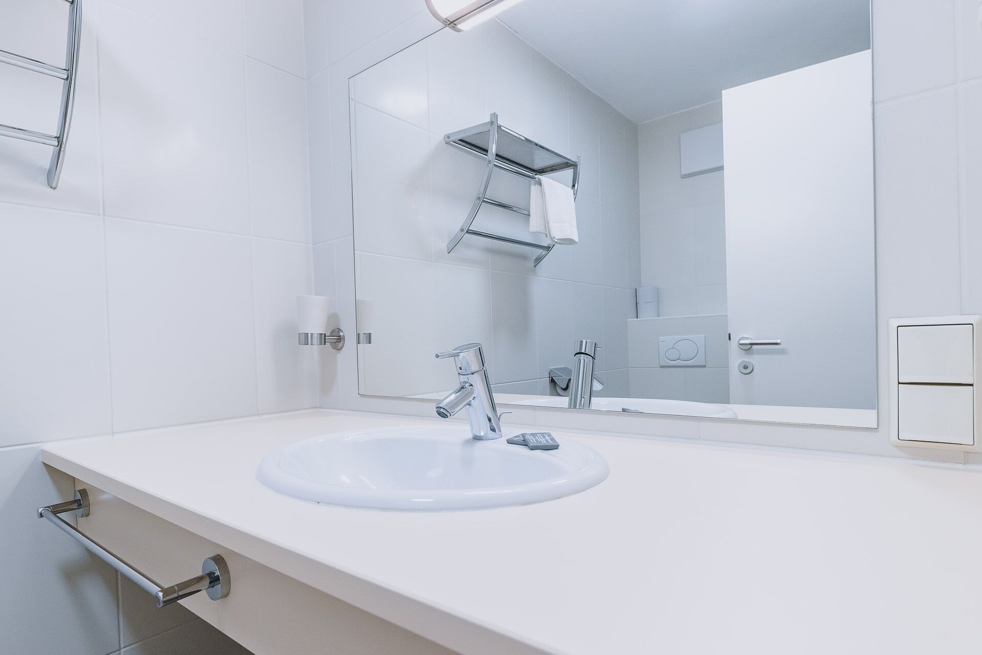 A modern bathroom with a white sink, chrome fixtures, and a large mirror.