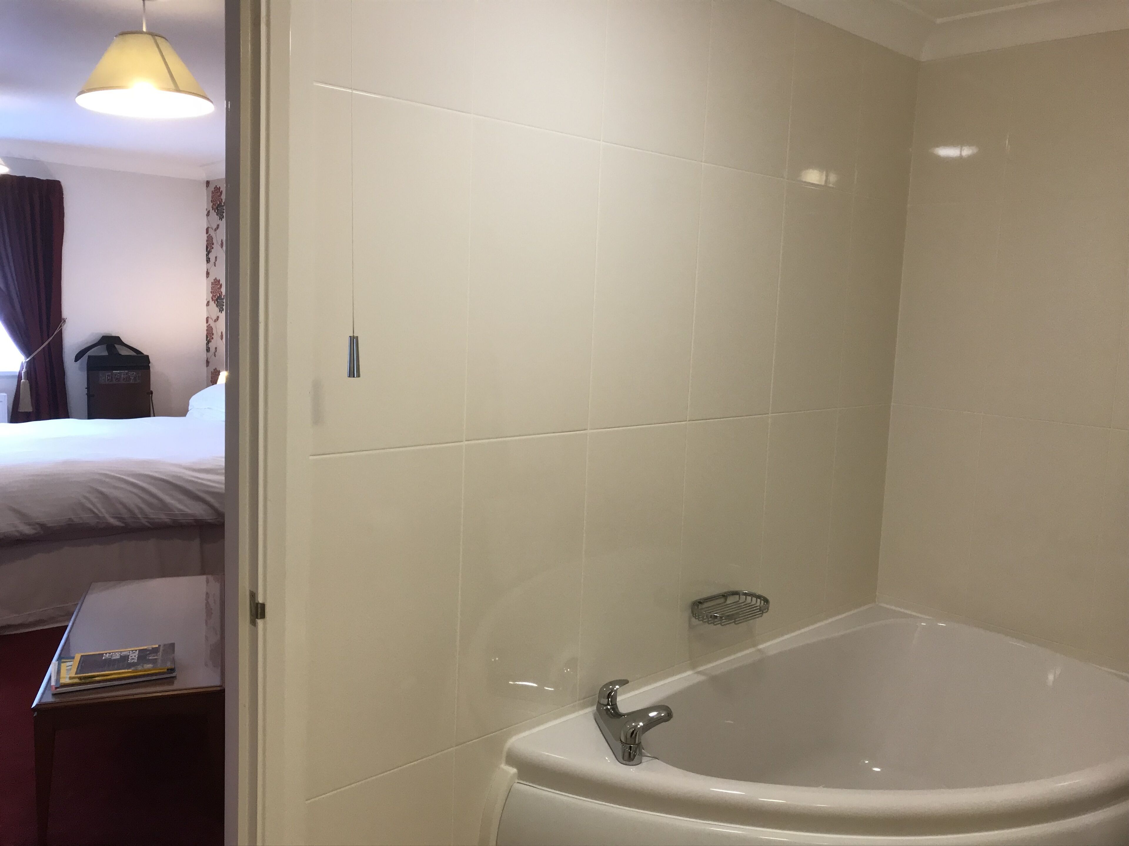 A bathroom with a bathtub, a towel rack, and a small table with a book.