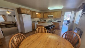 A kitchen with wooden cabinets, a refrigerator, a microwave, and a dining area with a wooden table and chairs.