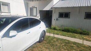 Un coche blanco estacionado frente a un edificio con el número 44715 en la pared.