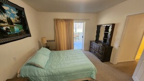 A bedroom with a bed, a dresser, a lamp, and a painting on the wall.