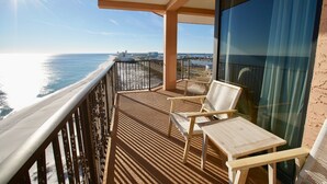 Un balcon avec vue sur l’océan, une table et deux chaises.