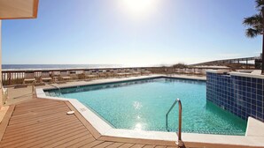 Une piscine avec une terrasse en bois et vue sur la plage.