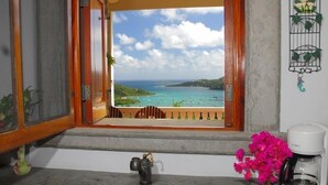 Un baño con vistas a una playa tropical, un lavabo, una cafetera y un reloj decorativo en la pared.