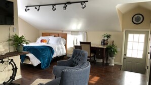 A bedroom with a bed, a desk, a chair, a TV, and a clock on the wall.