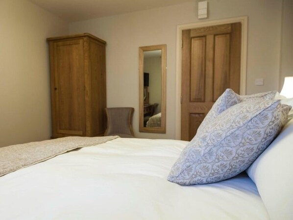 Un dormitorio con cama, un armario de madera, una silla y una puerta.
