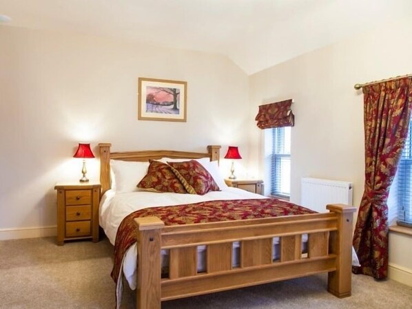 A bedroom with a wooden bed, two bedside tables with lamps, a window with curtains, and a framed picture on the wall. - Parkers House Bed & Breakfast (Newtown)