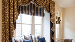 A cozy seating area with a window seat, patterned curtains, and a small table.