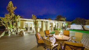 Un patio al aire libre con terraza de madera, sillas y una mesa.