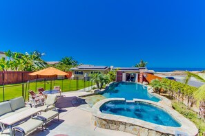 Um quintal com piscina, móveis de pátio e vista para o oceano.