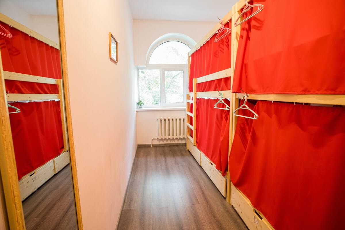 Un couloir étroit avec des lits superposés, une fenêtre et un radiateur.