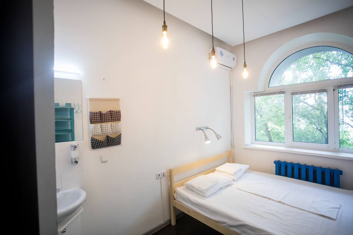 Une chambre à coucher comprenant un lit, une fenêtre, un radiateur et un luminaire fixé au mur.