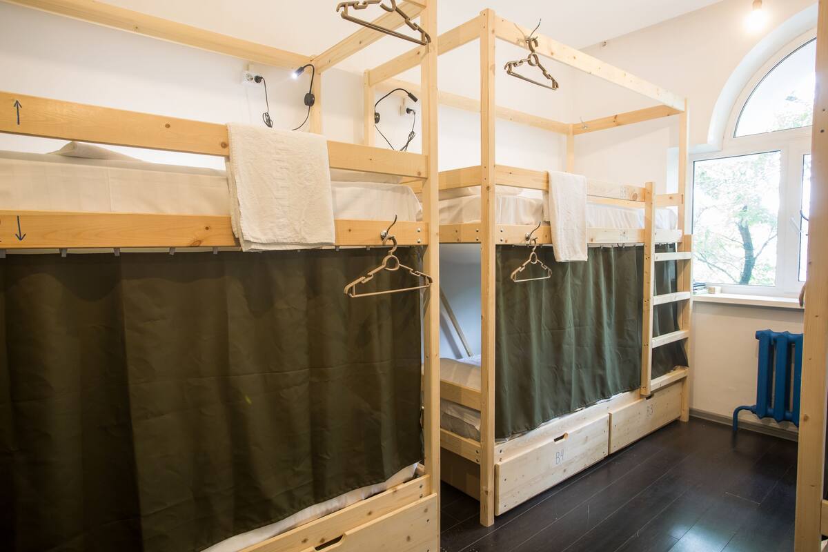 Une chambre de dortoir avec des lits superposés, une fenêtre donnant sur un beau paysage et un radiateur.