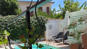 A swimming pool with a tiled deck, surrounded by lounge chairs and a garden with red flowers. - Beatrice Home B&B (Pompei)