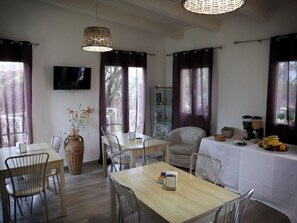 A dining area with a table set for four, a vase with flowers, and a television mounted on the wall. - Beatrice Home B&B (Pompei)