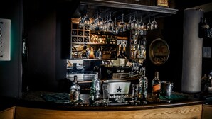 A bar area with shelves of liquor bottles, glasses, and a star logo on the wall. - Havana Hotel Cairo (Giza)