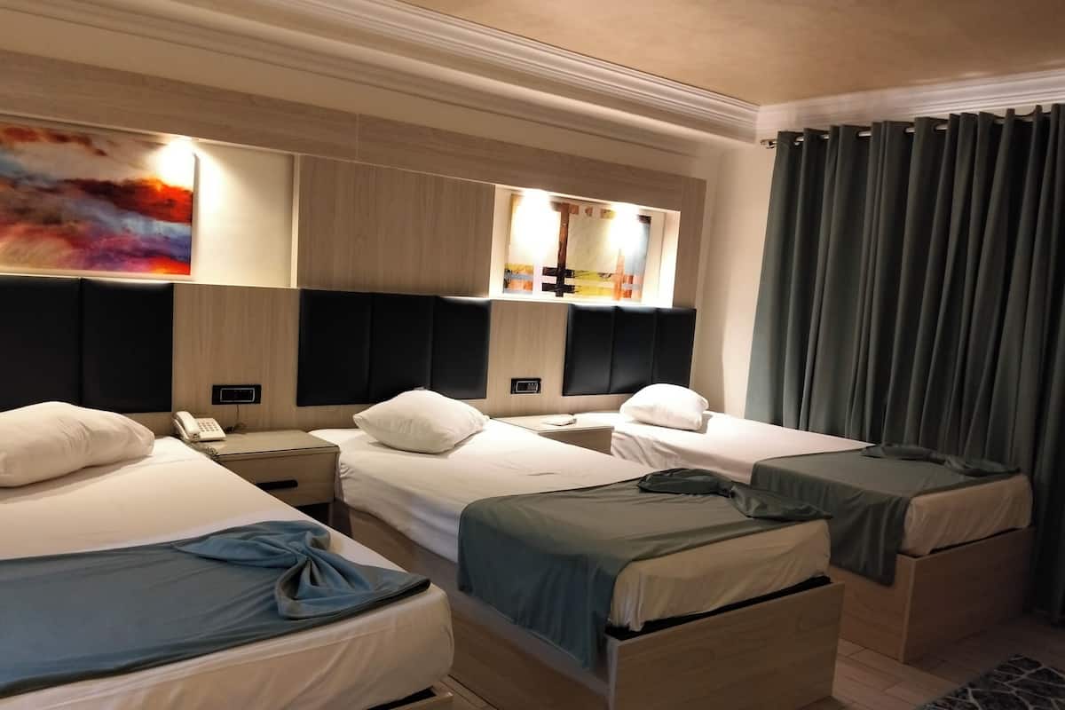 Une chambre d’hôtel avec deux lits, un bureau, un téléphone et un tableau au mur.