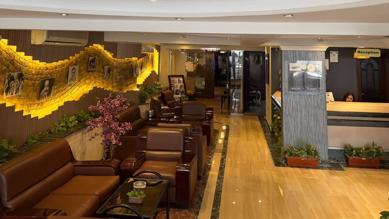 A hotel lobby with leather seating, a reception desk, and a staircase with photos.