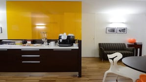 A compact living space with a kitchenette, a sofa, a dining table, and a small side table.