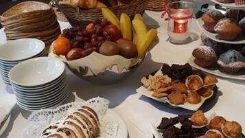 A buffet table with various food items including pastries, fruits, and desserts.