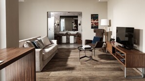 Ein modernes Wohnzimmer mit Sofa, Couchtisch, TV-Schrank und einer Küchenzeile im Hintergrund.