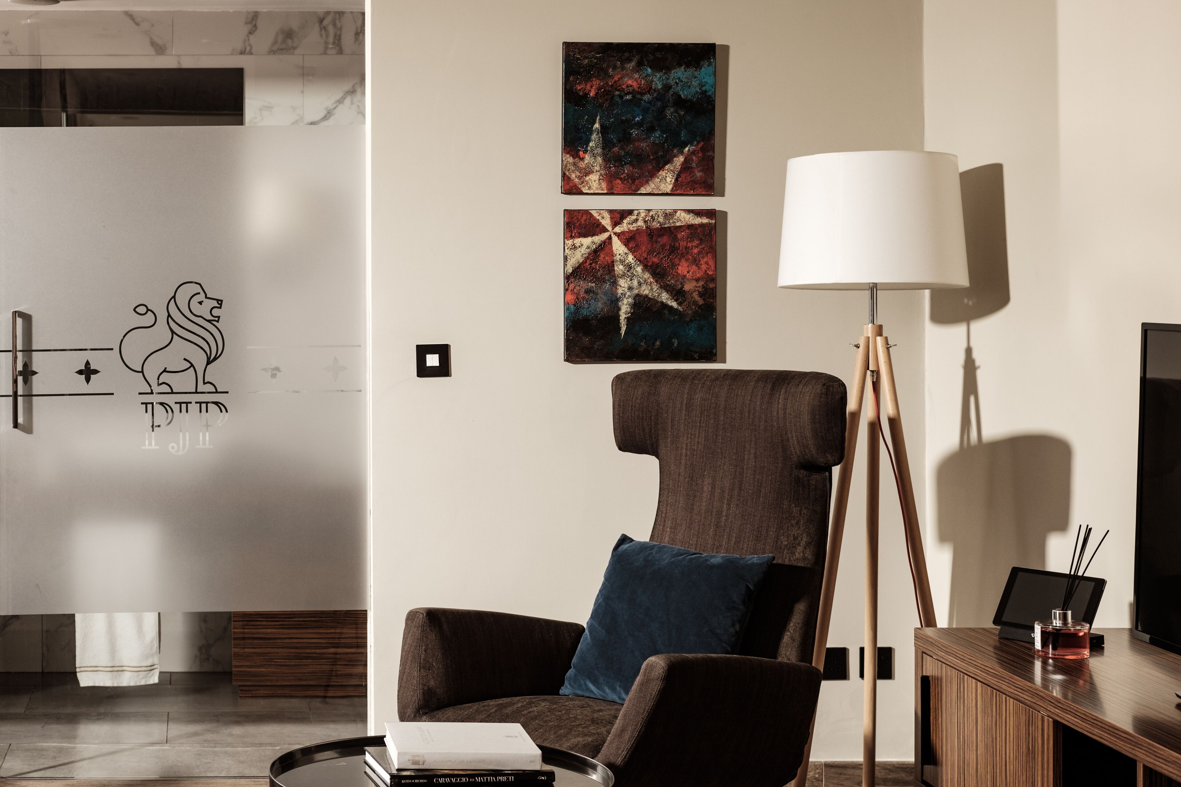 Een moderne kamer met een bruine fauteuil, een staande lamp en abstracte wanddecoratie.