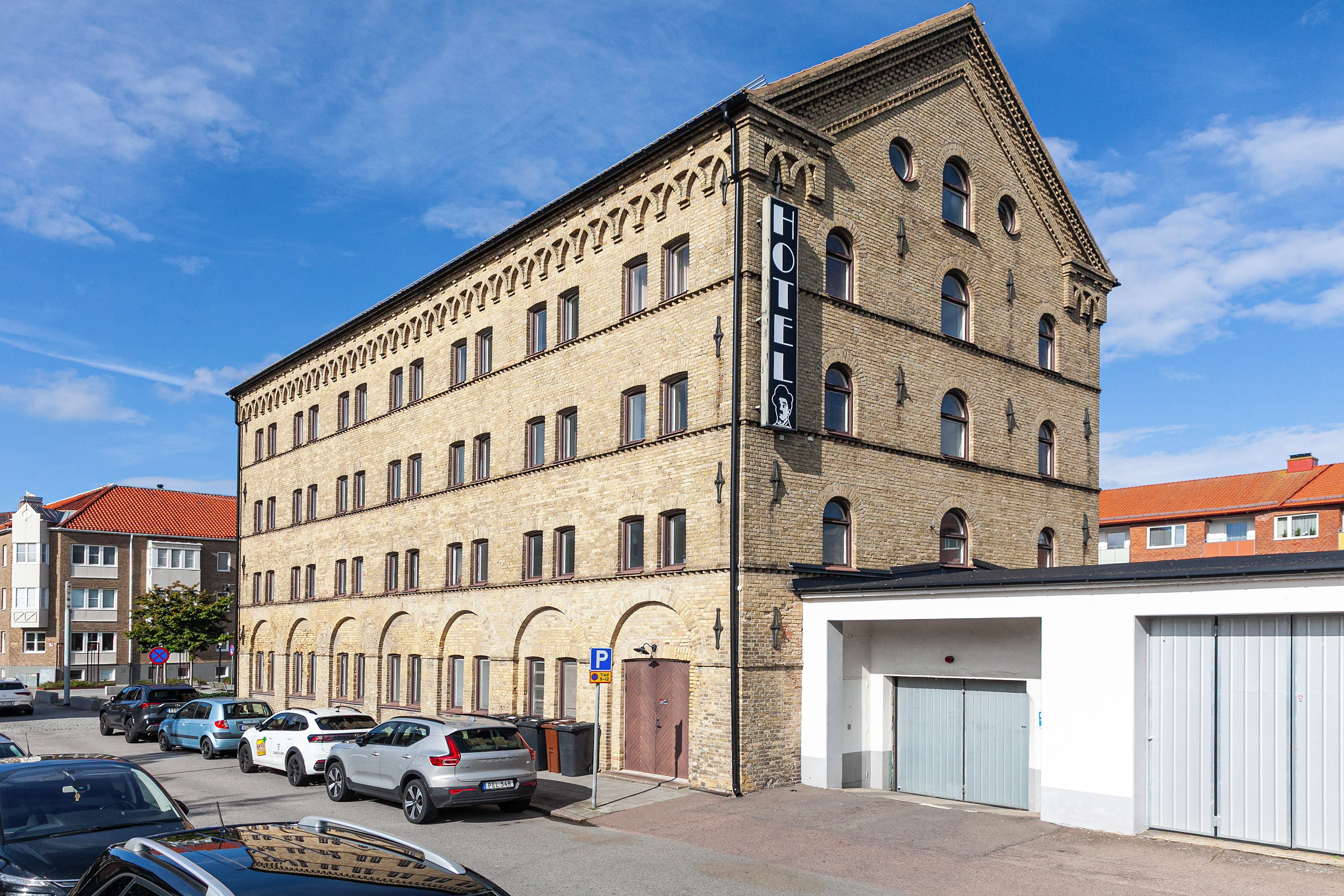 Ett hotell med flera våningar, en fasad av tegel, många fönster och ett garage på markplan.