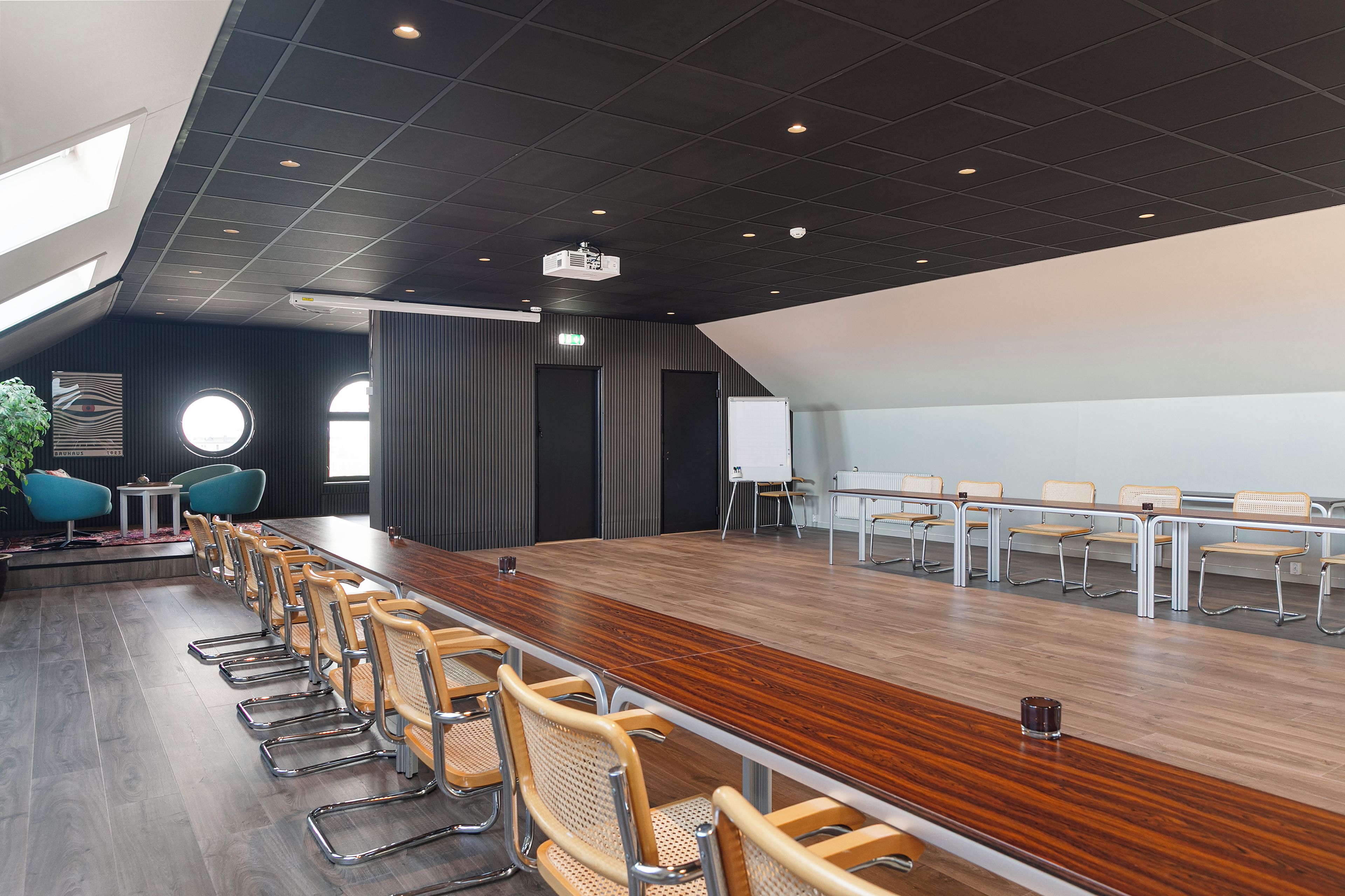 Ein Konferenzraum mit einem langen Tisch, Stühlen, einer Tafel und einem Projektor.