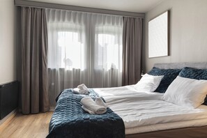 Ein Hotelzimmer mit Bett, Vorhängen und einem an der Wand hängenden Kunstwerk.