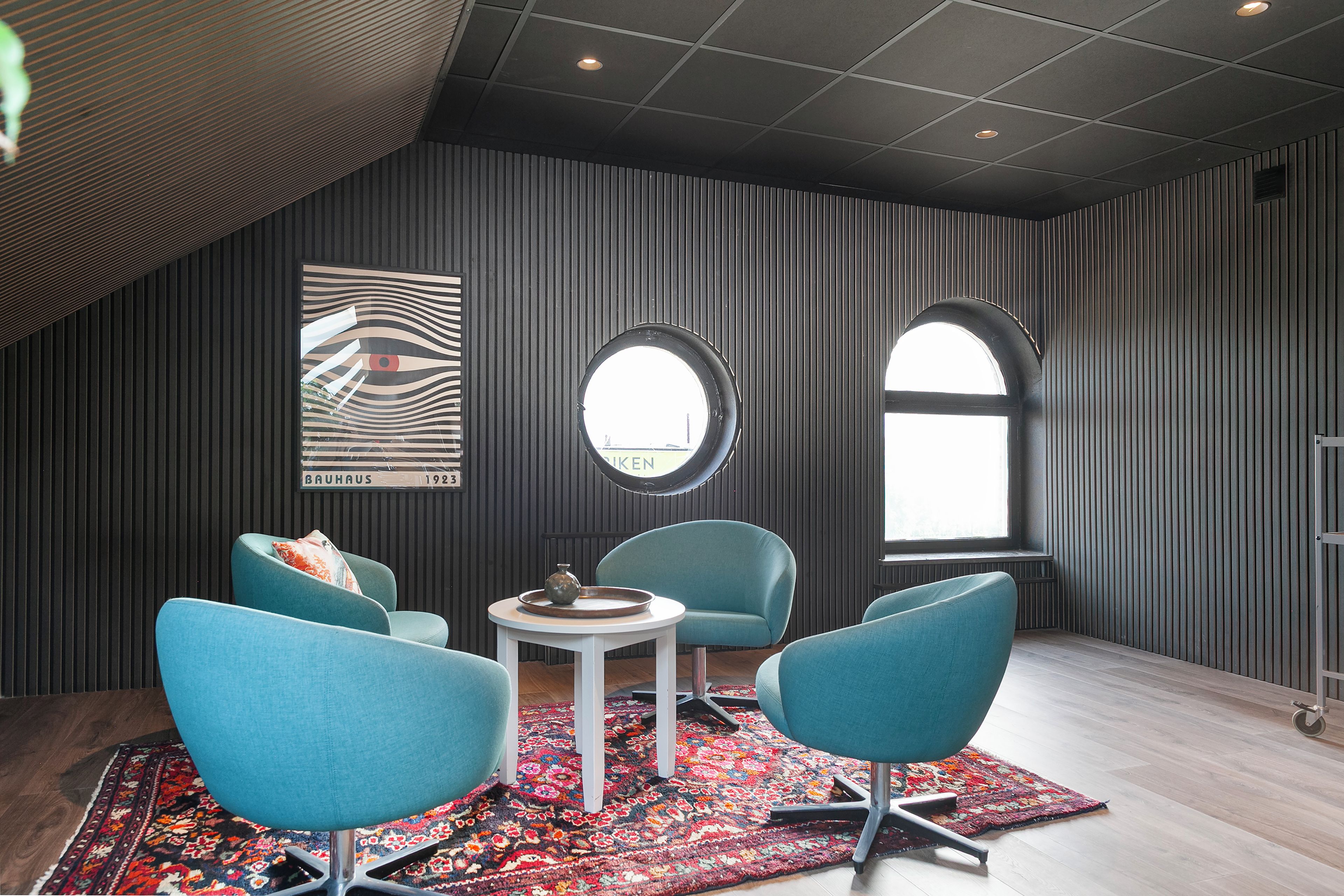 Un salon moderne avec un plafond haut, un mur orné de motifs et une grande fenêtre.