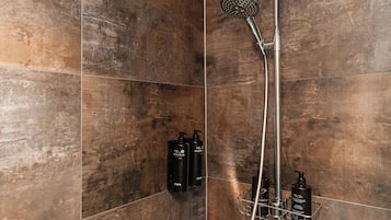 Ein Badezimmer mit Dusche, gefliesten Wänden und einem Metallregal mit Flaschen.