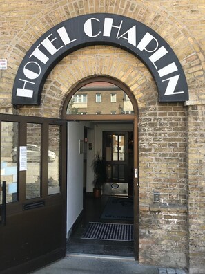 La entrada al Hotel Chaplin, con fachada de ladrillo y un cartel arqueado sobre la puerta.