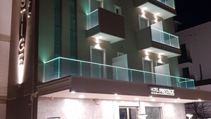 Un hotel moderno con varios balcones, un cartel llamativo que dice "HOTEL PRESTIGE" y una fachada bien iluminada.