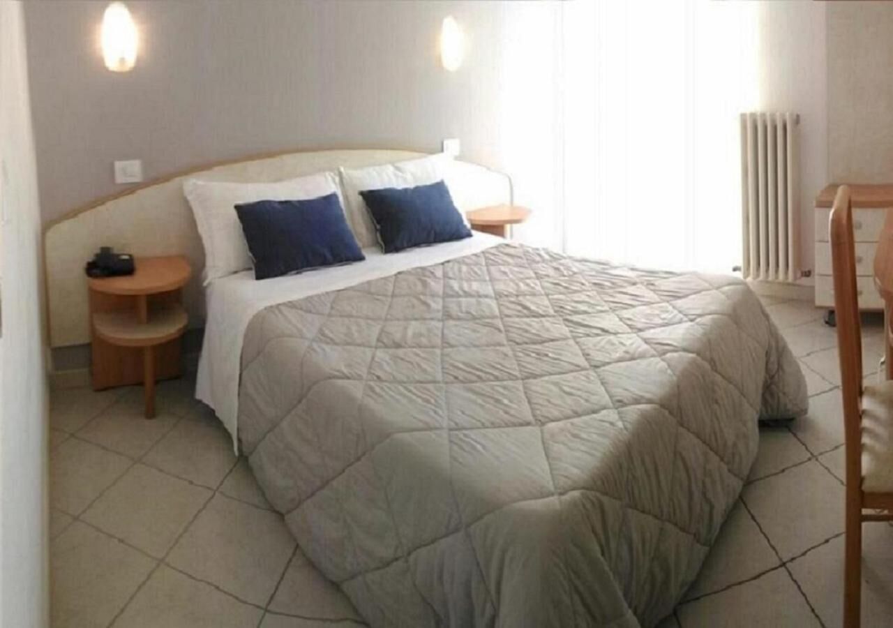 A neatly made bed with a quilted cover, two bedside tables with lamps, and a radiator on the wall.