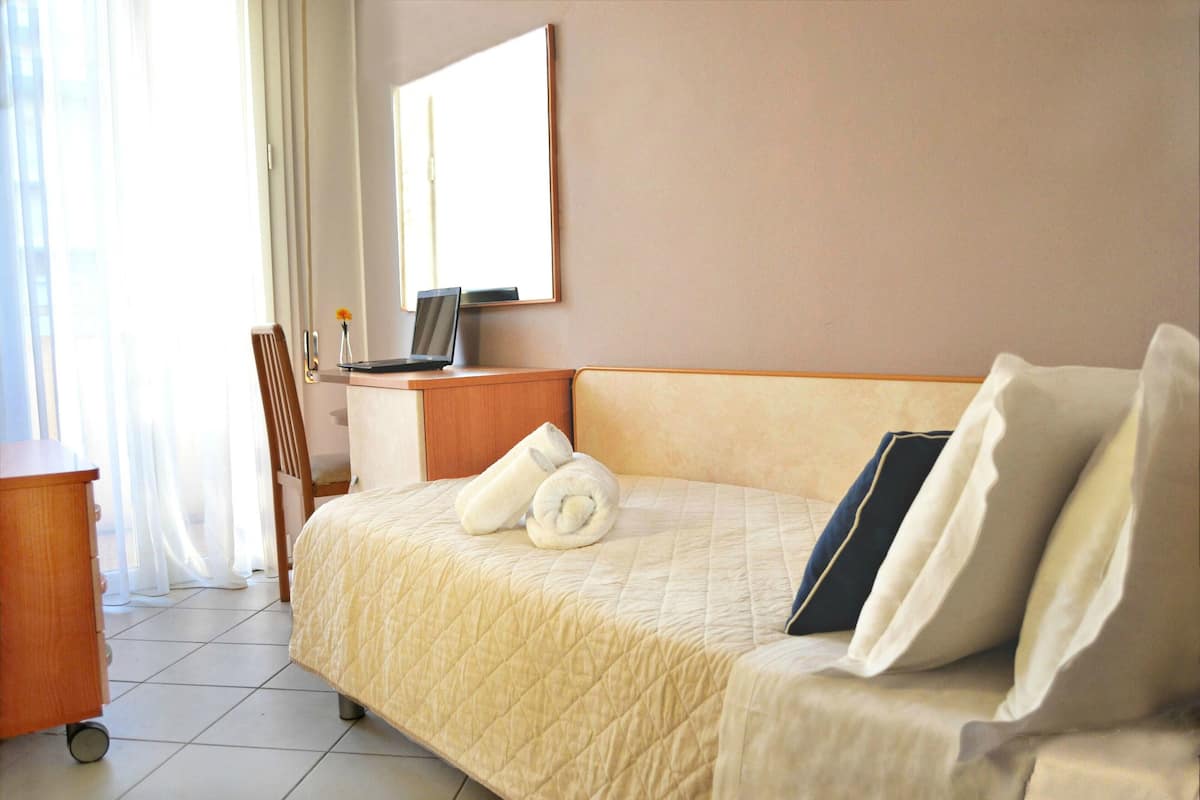 Una habitación de hotel con cama, escritorio, silla y espejo.