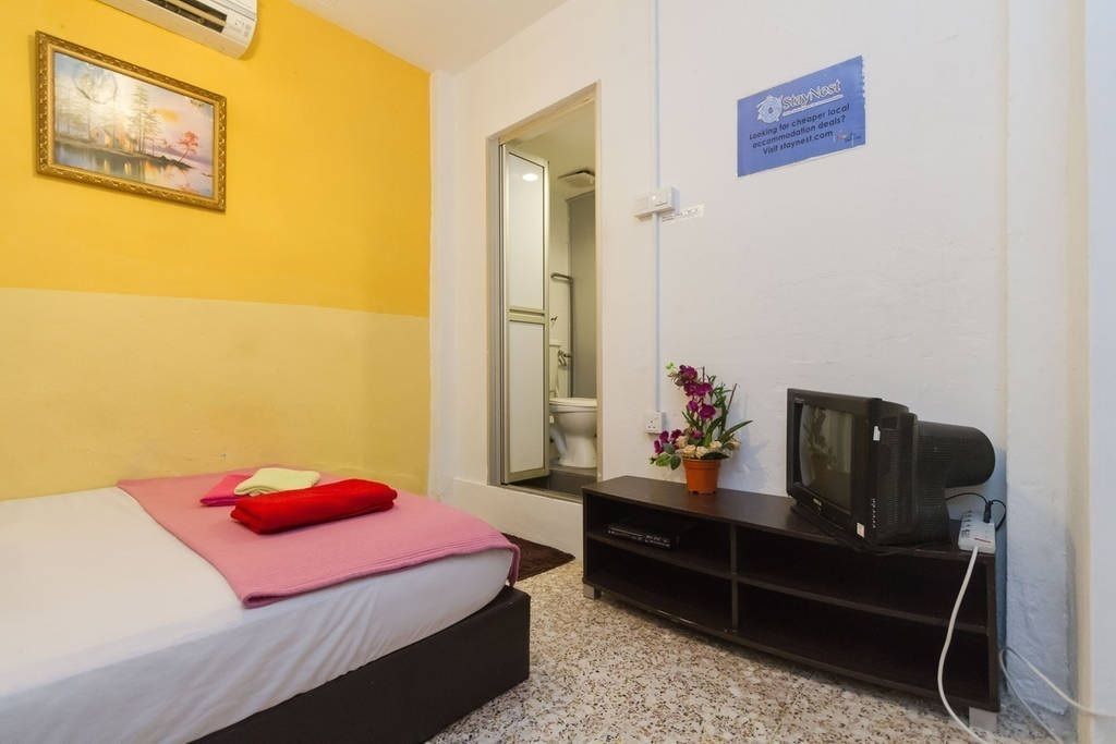 A hotel room with a bed, a TV, and a sign advertising local accommodation deals.