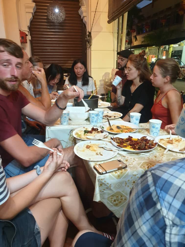 A group of people seated around a table with plates of food, engaged in conversation.