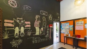 Eine Wand mit Kreidezeichnungen von Personen, einem Schild für eine Bushaltestelle und einem Hinweis auf einen Waschservice.