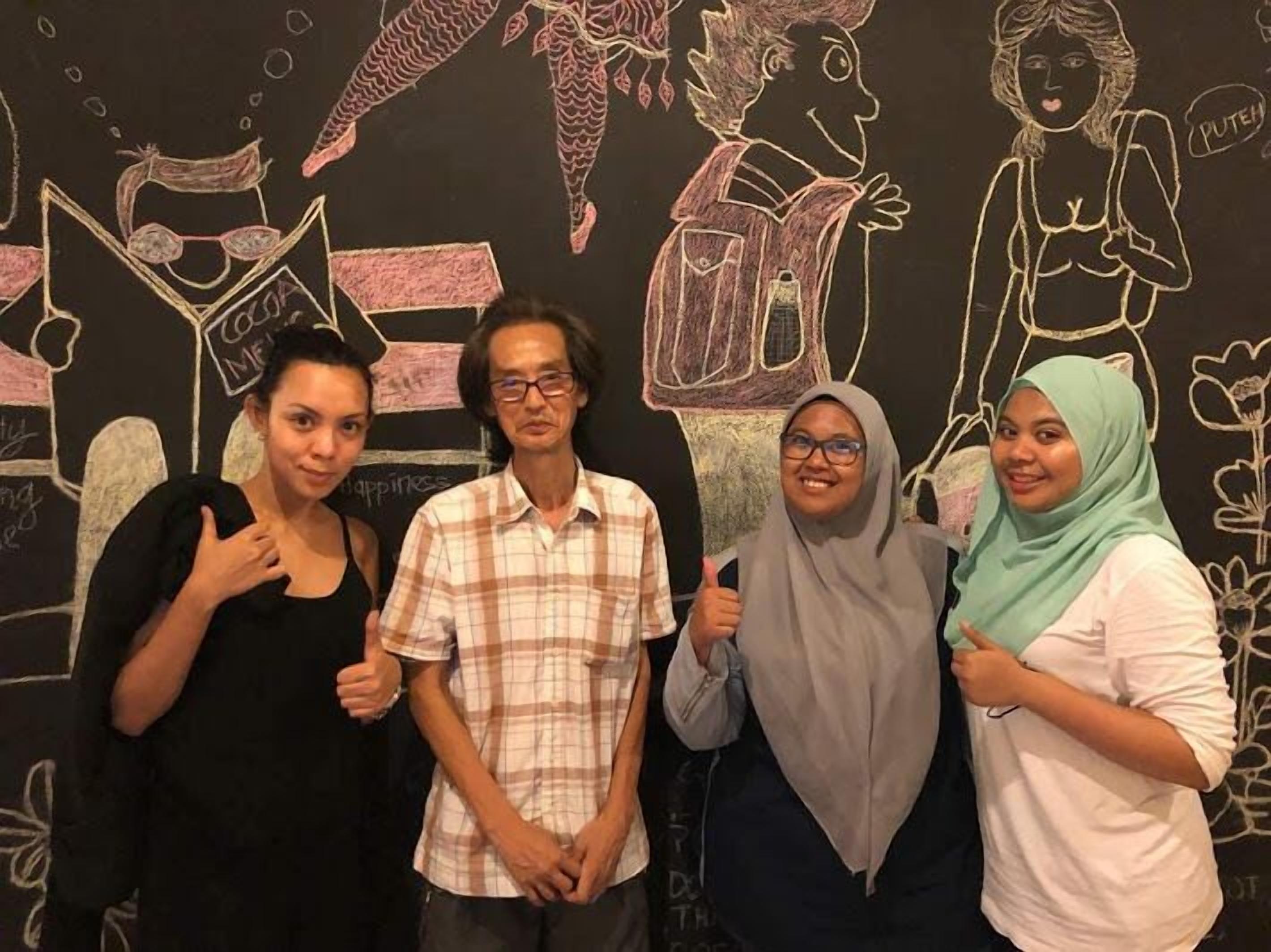 A group of people standing in front of a wall with chalk drawings.