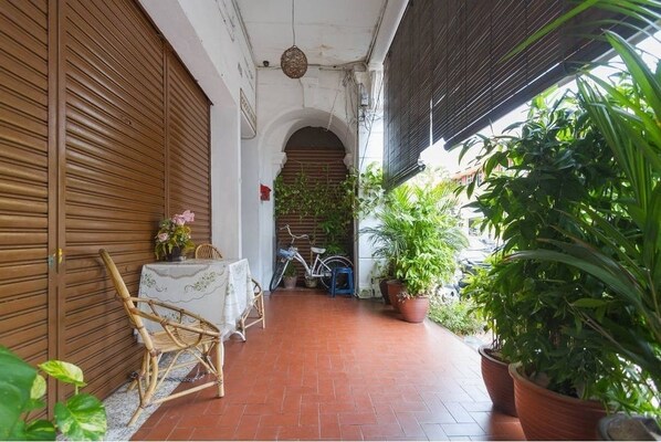 A covered outdoor area with a table, chairs, and potted plants.