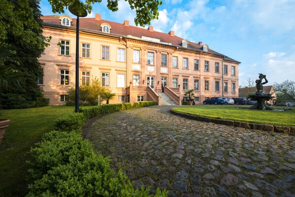 A large, historic building with a cobblestone pathway leading to the entrance. - Schlosshotel Rühstädt GARNI (Ruehstaedt)