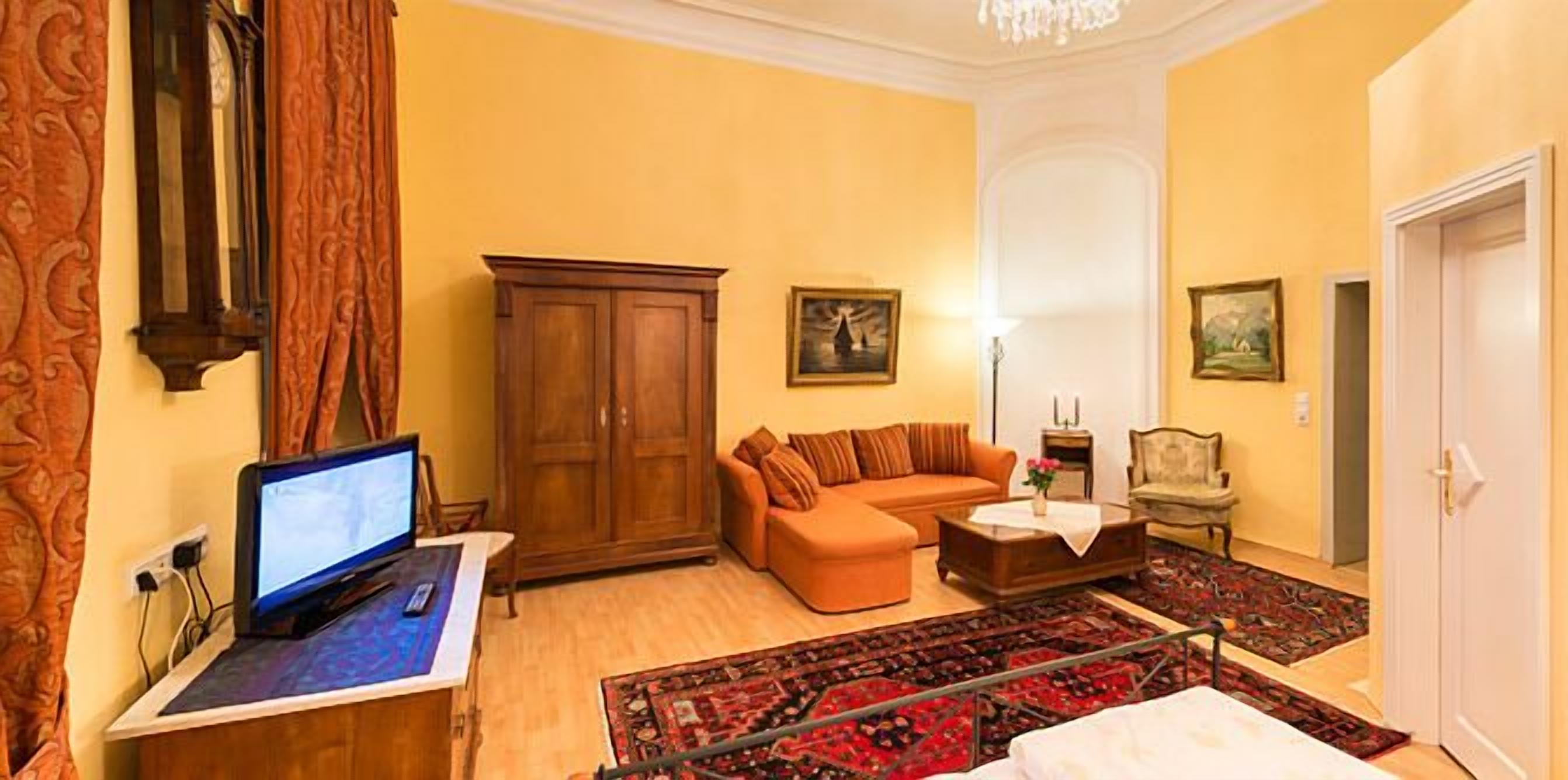 A living room with a sofa, a wooden cabinet, a television, and a patterned rug.