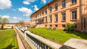 Een groot, meerlaags gebouw met een symmetrische gevel, een verzorgd gazon en een stenen balustrade.