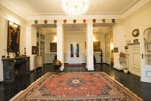 A grand hallway with a large ornate rug, a chandelier, and a fireplace. - Schlosshotel Rühstädt GARNI (Ruehstaedt)