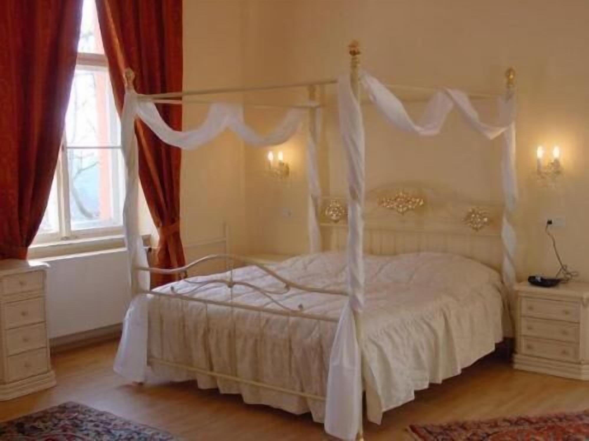 Una cama con dosel y cuatro columnas, con ropa de cama blanca, una mesita de noche y un aparador.