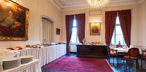 A formal dining room with a long table set for a meal, a chandelier, and a large portrait on the wall. - Schlosshotel Rühstädt GARNI (Ruehstaedt)