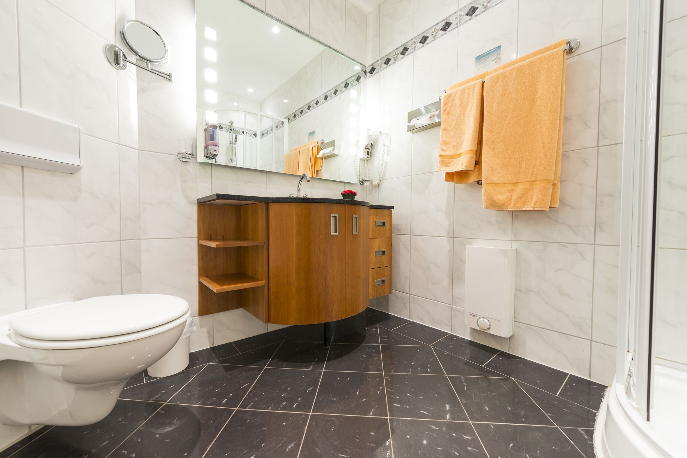 Een moderne badkamer met toilet, wastafel en douchehoek.