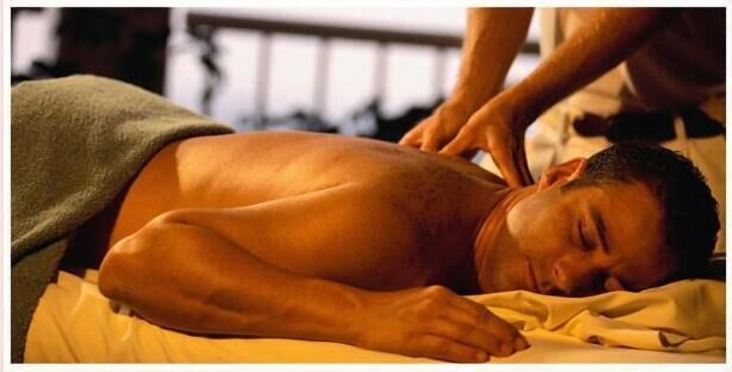 A person lying on a bed receiving a massage.